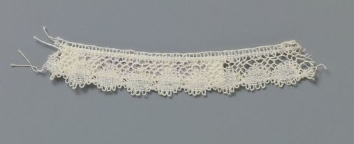 Strip of bobbin lace with linked small ovals along the bottom