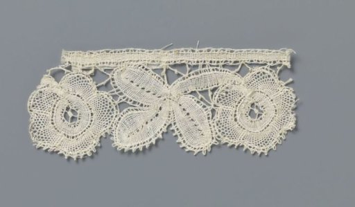 Strip of bobbin lace with a three-lobed leaf between two rosette flowers