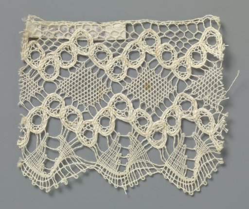 Strip of bobbin lace with diamonds between zigzag lines of openwork circles
