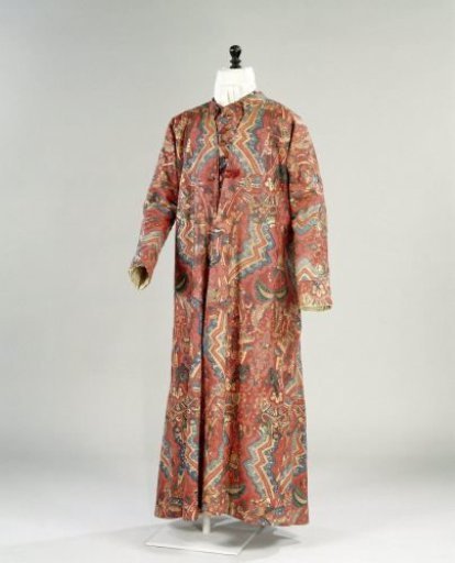 Long sleeveless jacket of chintz with a red ground, decorated with coloured zigzag borders, surrounded by abstract floral motifs; lining and back of linen
