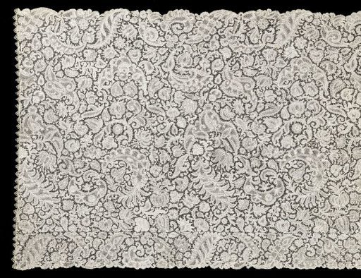 Strip of bobbin lace with all kinds of flowers and C-scrolls between feathered leaves