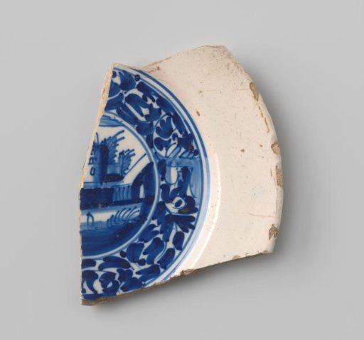 Sherd of white-fired earthenware with white glaze on the upper and lower sides, with remains of a bordered representation of a landscape with buildings in blue visible on the upper side