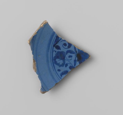Plate fragment of yellow-fired earthenware, glazed blue on the upper and lower sides, with a stylized painting of flowers surrounded by stripes on the flat surface in blue