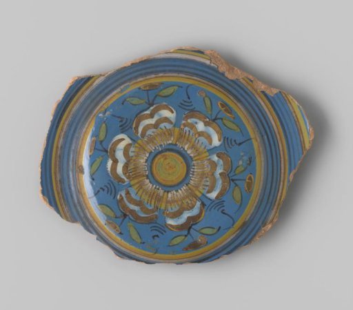Sherd of reddish-fired earthenware with blue glaze on the upper side, decorated on the flat with a painting of a circled flower in white, brown, yellow, green and black