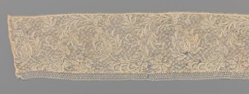 Strip of bobbin lace with a plume-shaped flower on a C-shaped leaf