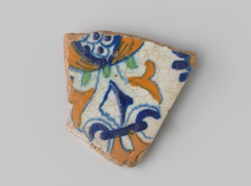 Fragment of a tile with a red-fired shard, with white glaze, featuring a drawing in blue, green, and orange of (part of) a pomegranate and ornaments.