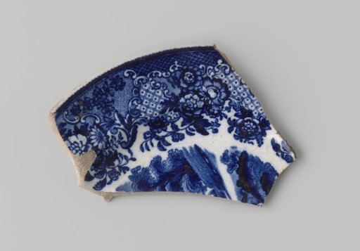 Fragment of a plate of white-firing earthenware, with a printed decoration on the front featuring flowers and part of a landscape in blue