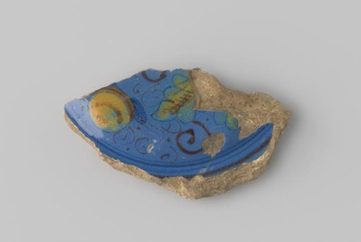 Fragment of a plate of white-firing earthenware, with blue glaze on the front featuring a polychrome representation of a fruit and leaves