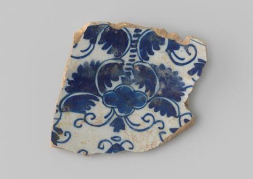 Fragment of a plate of white-firing earthenware, with white glaze on the front featuring a drawing of floral forms in blue