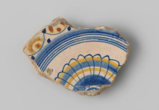 Fragment of white-firing earthenware, with a painting of circles and a flower shape in blue, yellow and orange on the upper side