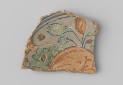 Fragment of red-firing earthenware, with a painting of an orange fruit with blue twigs and green leaves on the upper side