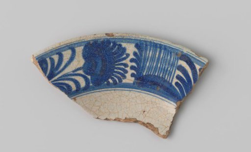 Fragment of red-firing earthenware, with a painting of a floral border in blue on a white ground on the upper side