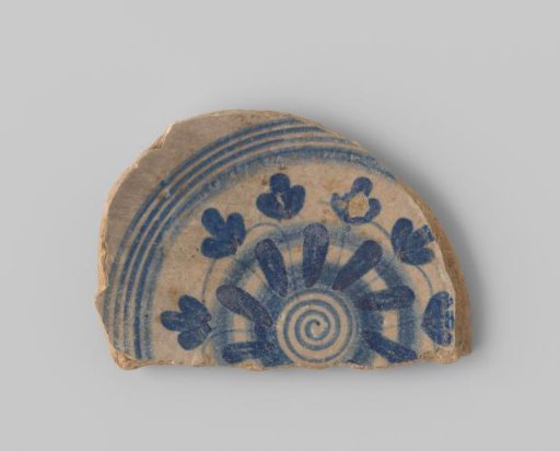 Fragment of white-firing earthenware, with a painting of a flower in blue on a white ground on the upper side