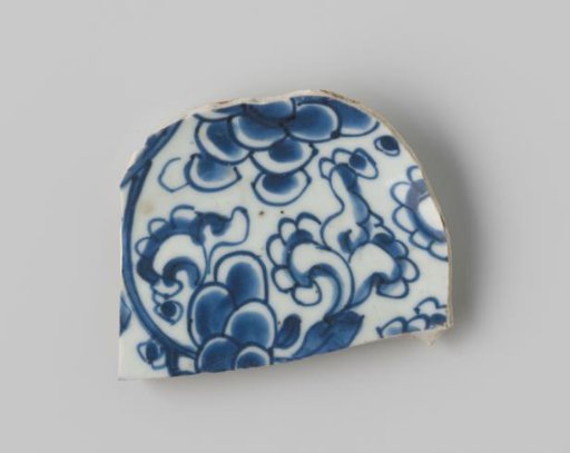 Fragment of porcelain, with a painting of flower shapes in blue on a white ground on the upper side