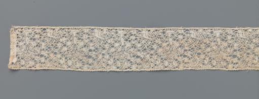 Strip of bobbin lace with a drop-shaped motif in a tangled pattern of curves