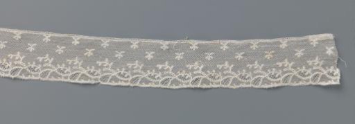 Strip of bobbin lace with tilted ovals under a scattering pattern of twigs