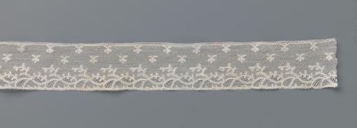 Strip of bobbin lace with tilted ovals under a scattering pattern of twigs