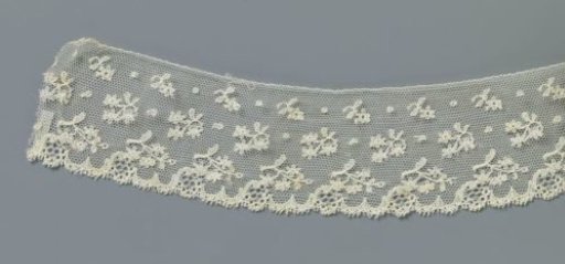 Strip of machine lace with three rows of flower branches and w-shaped motifs along the underside