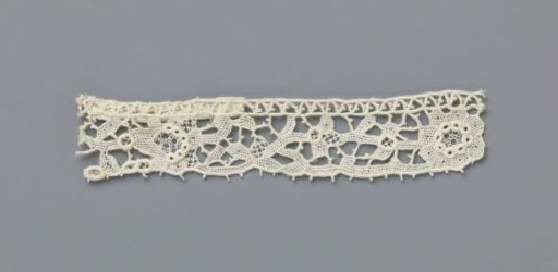 Strip of needle lace with various flowers in a row on a vine and thick festooned circles