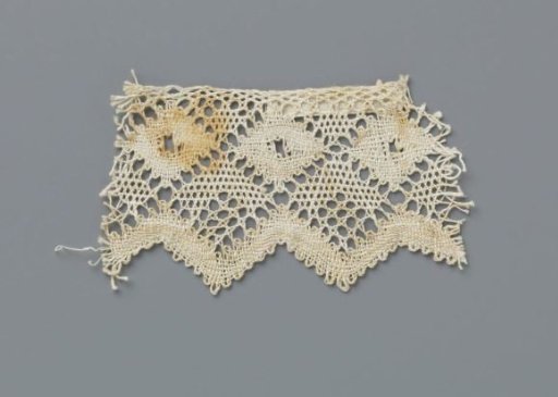 Strip of bobbin lace with a row of diamonds and a wavy shell border