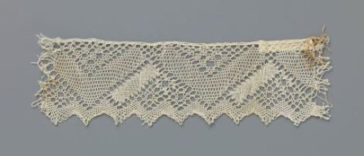 Strip of bobbin lace with V-shaped motifs and zigzag shell edge