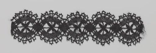 Strip of black bobbin lace with wheels and semicircular scallops on two sides