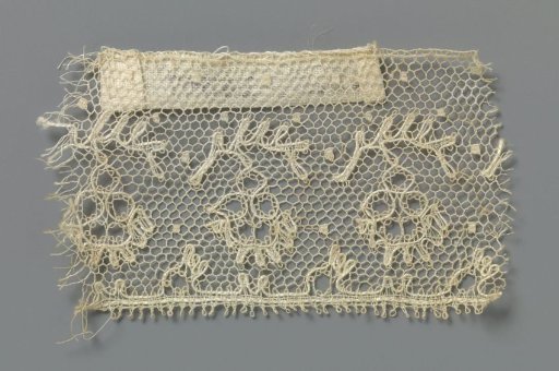 Strip of bobbin lace with flower under curved leaf