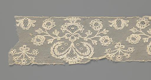 Border of bobbin lace with two volute leaves in a vase