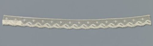 Strip of machine-made lace with a row of snowflakes above a wavy shell border