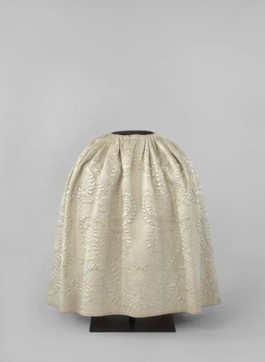 Skirt with two side slits and white linen lining of quilted and stitched white satin; the skirt is pleated all around with smooth panel at the front