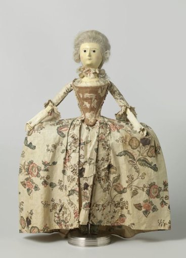 Wooden Doll with Glass Eyes and a Wig of Human Hair, Dressed in a Jacket (Demi-Parure) of Printed Cotton, Consisting of a Jacket and an Apron