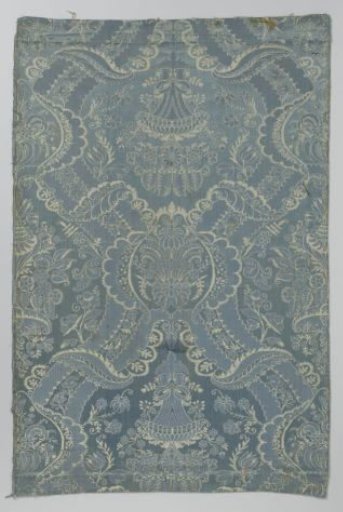 Fragment of blue and white silk fabric with a pattern of stylized flowers and vases and festooned sculpted bands, leaves and flower branches