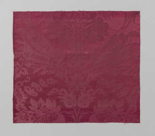 Fragment of red silk damask with a pattern of a vase-shaped stylized flower surrounded by curved, heart-shaped leaves