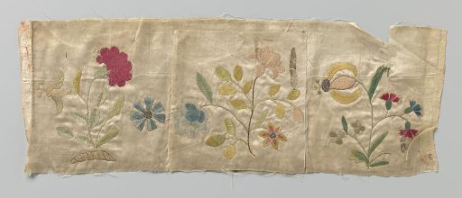 Fragment of white satin with colored silk flowers