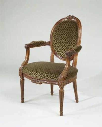 Armchair made of mahogany, with conical, fluted legs and a front stretcher decorated with a bow. Upholstered in green patterned velvet with rosettes. Upholstery not original.