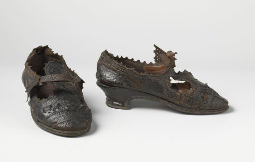 Shoe of Black Calfskin with Low Clog Heel, Round Toe and a Front Flap Ending in a Flap Over Which a Strap