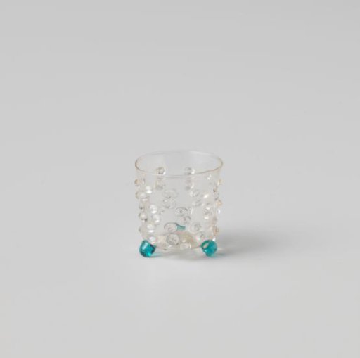 Cup decorated with knobs and studs, on three ball feet