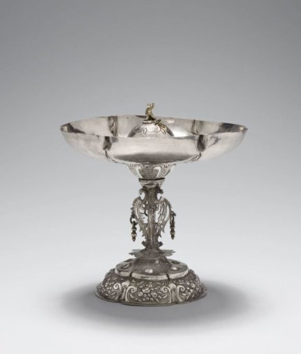 Hansje in the Cellar. The bowl is decorated with chased fruit clusters and has a half-sphere in the center with a hinged lid under which sits a gilded child figure.