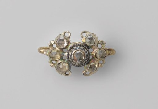 Pin of (gilded) silver in the shape of a bow, decorated with seven imitation diamonds