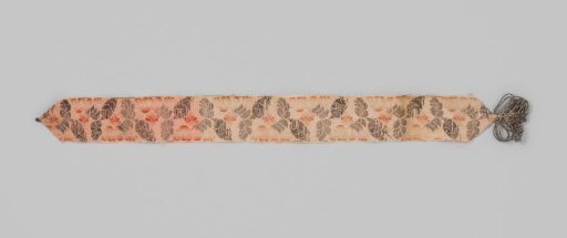 Garter of beige silk with a lance effect; the garter is decorated with flowers and leaves in silver and orange; with silver torsade