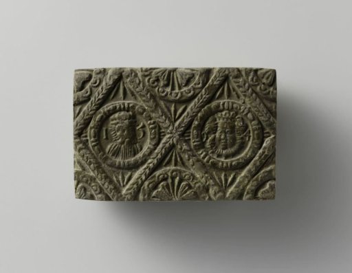 Fireplace of baked clay with a diamond-shaped division, with two medallions featuring a man's head and a woman's head and face