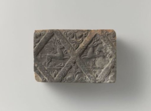 Fireplace of baked clay with a diamond-shaped division, with two winged stags in two diamonds