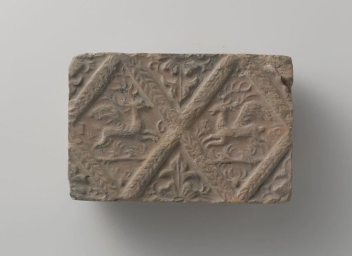 Fireplace of baked clay with a diamond-shaped division, with two winged stags in two diamonds