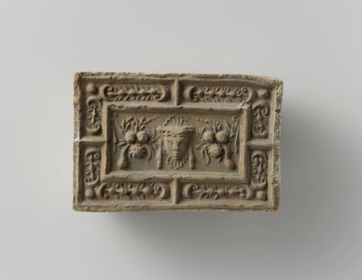 Fireplace surround with a representation of a mask between two fruit festoons