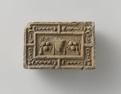 Fireplace surround with a representation of a mask between two fruit festoons