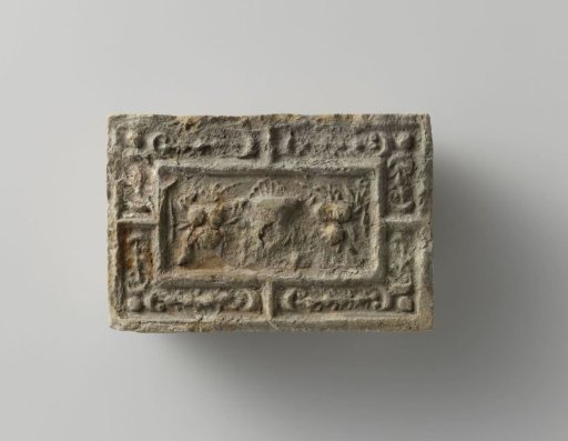 Fireplace surround with a representation of a mask between two fruit festoons