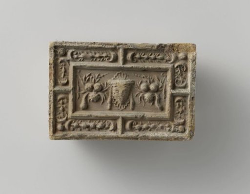 Fireplace surround with a representation of a mask between two fruit festoons