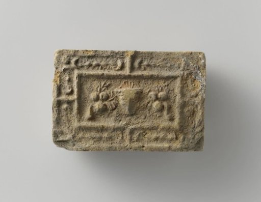 Fireplace surround with a representation of a mask between two fruit festoons