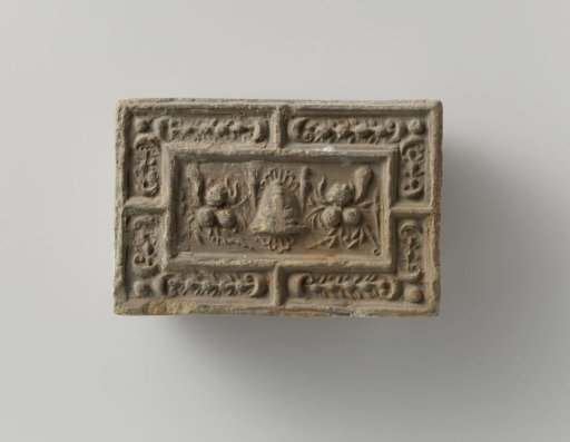 Fireplace surround with a representation of a mask between two fruit festoons