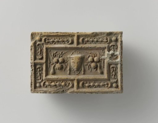 Fireplace surround with a representation of a mask between two fruit festoons